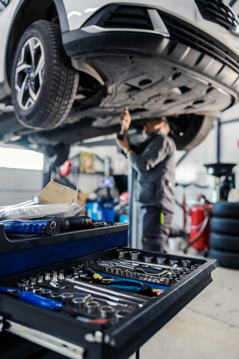 A mechanic doing safety inspection checks as part of car servicing package in a garage.