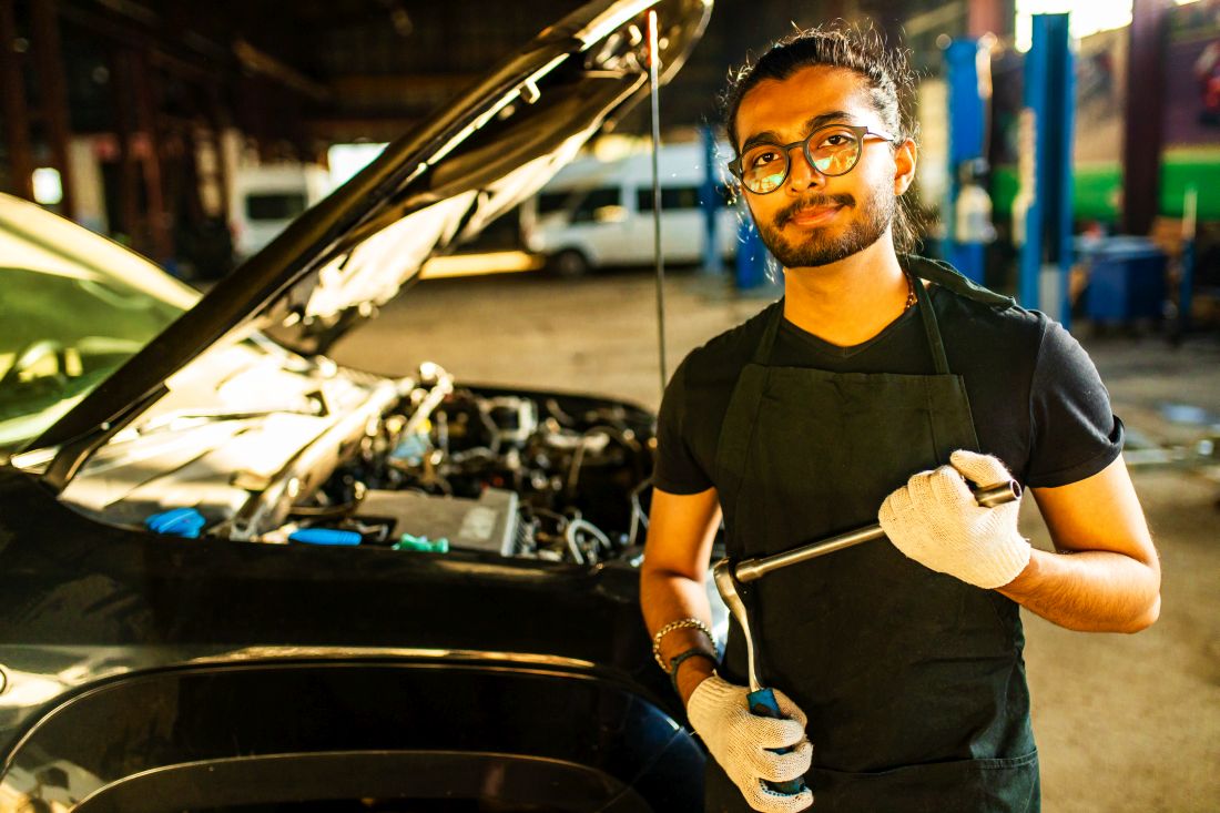 A Hybrid Car Specialist mechanic standing in front of a hybrid car in Jackson PowerTrain.