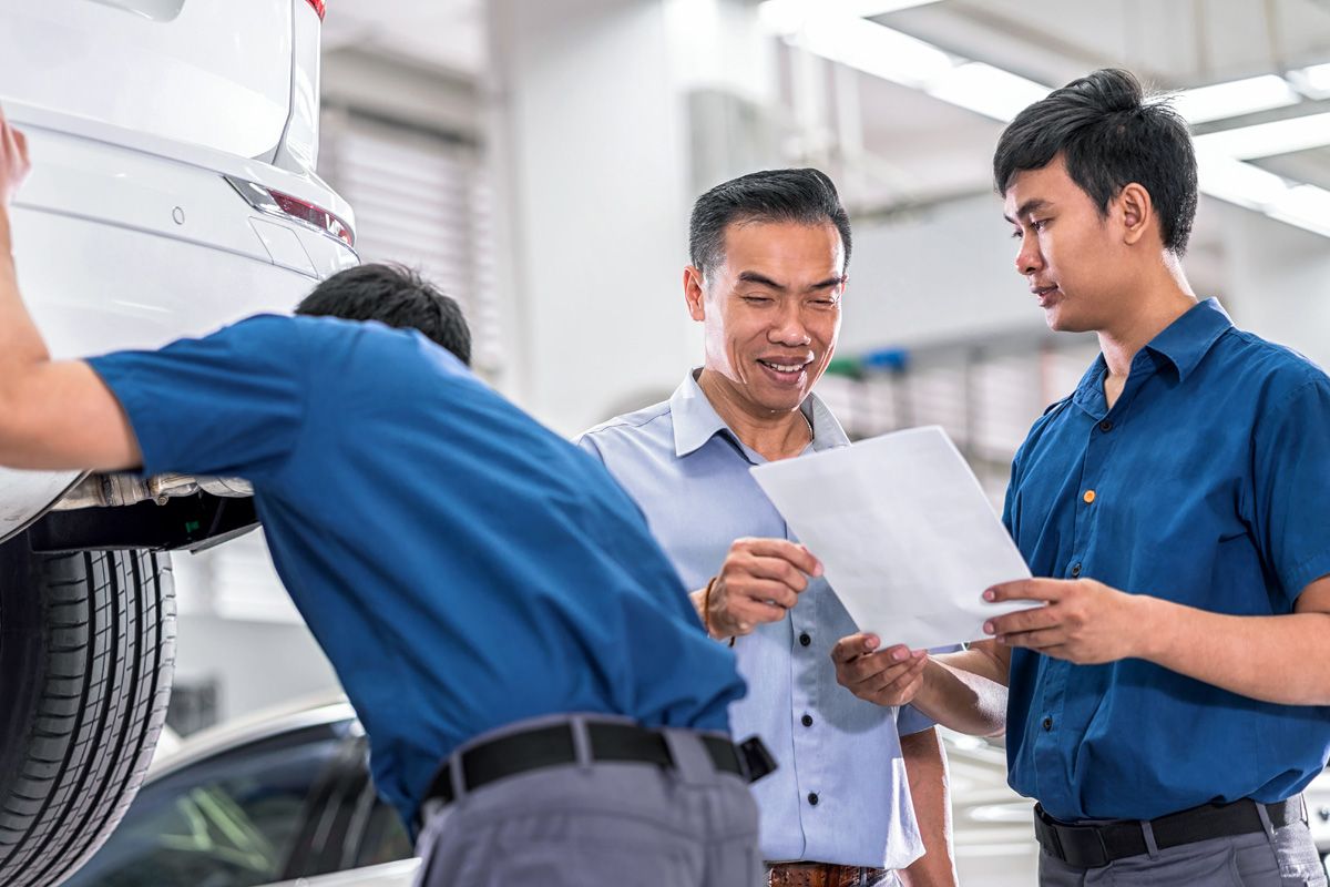 Jackson Powertrain car servicing specialist inspecting a car with customer in automotive repair as part of the car care program.